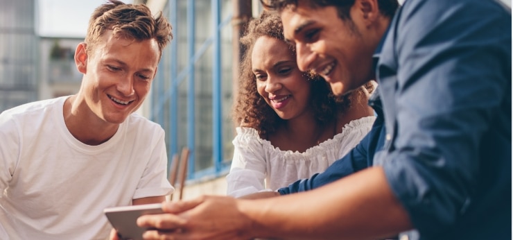 Tres clientes de Spectrum Mobile mirando un teléfono móvil.